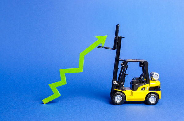 A yellow forklift raises a big green arrow up. Growth in production rates and development of industry and infrastructure. Increased sales, economy growth. Concept of increase, growth and success.