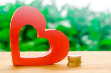 Tahta kırmızı kalp ve bir yığın bozuk para. Sağlık kavramsal politikası, sağlık finansmanı, araştırma ve geliştirme büyüdü. Para için kavramı. Seçici odaklama