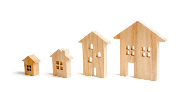 Four wooden houses stand in ascending order on a white background. Isolate The concept of increasing population density and high-rise buildings. Agglomeration and urban growth. Selective focus — Stock Photo, Image