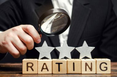 Not veren tahta bloklar, üç yıldız ve bir işadamının elinde büyüteç. Hizmet kalitesi kavramı. Otel ya da restoran derecesi. Eleştirmenlerin ve ziyaretçilerin değerlendirilmesi.