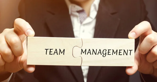 Businessman collects puzzles with the words Team management. Increase efficiency. Hiring and dismissal employees. Organization of working business process. Distribution of roles and responsibilities