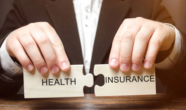 Businessman collects wooden blocks with the word Health insurance. Health care concept. Cash costs for medical care. Financial support. Accidents, diseases, disability. Employee insurance. Agent