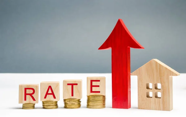 Holzklötze mit dem Wort Rate, Pfeil nach oben und Holzhaus. das Konzept, die Zinssätze für Hypotheken zu erhöhen. steigende Zinsen für das Darlehen. Steuersätze sind eine Art Grundsteuer — Stockfoto