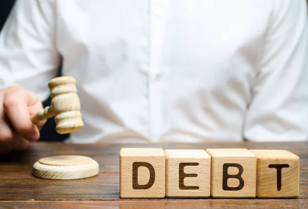 「借金」という言葉を持つ木製のブロックと、ガゼルで判断します。債務不払いに対する司法罰の概念。財産の負債。脱税/回避。破産と金融危機 — ストック写真