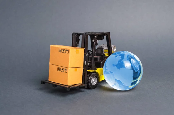 Stivuitor care transportă cutii și planeta albastră glob de sticlă pământ. Conceptul de comerț și comerț, livrare de mărfuri, schimb de mărfuri. Globalizare, pieţe. Afaceri și industrie, infrastructură de transport — Fotografie, imagine de stoc