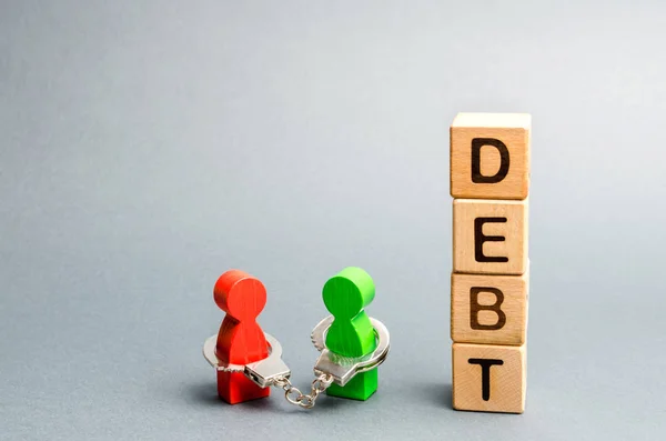 Two people are bound by handcuffs with the word Debt. Creditor and debtor. Financial slavery. Unclosed commitments. Blackmail and illegal pursuit. Psychological pressure. Debts relief. Debt pit. — Stock Photo, Image