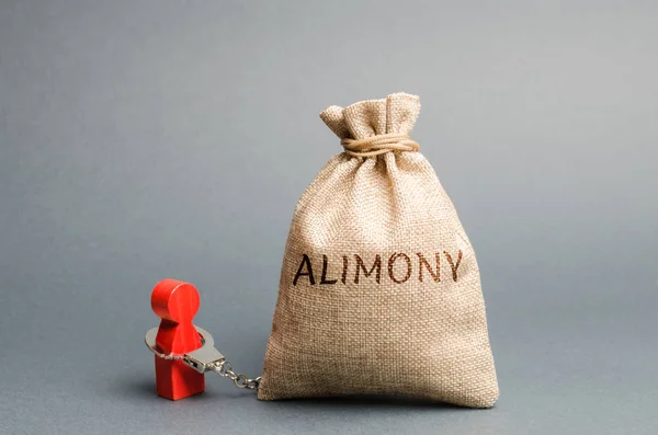 The man is handcuffed to a money bag with the word alimony. The concept of child support. Payments after a divorce. Financial support. Legal obligation. Support for disabled family members