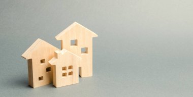Gri bir arka plan üzerinde minyatür ahşap evler. Emlak. Uzun süreli kiralık daireler. Genç aileler için uygun fiyatlı konut. Ucuz emlak kredileri. Mortgage ve kredi. Yeni binaların inşaatı