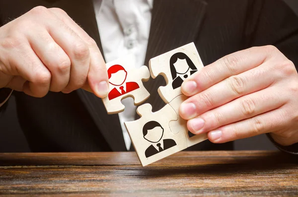 A businessman collects puzzles symbolizing a team of employees. The concept of the organization of the team and the business hierarchy. Management. The appointment of the head. Dismissal employee. — Stock Photo, Image