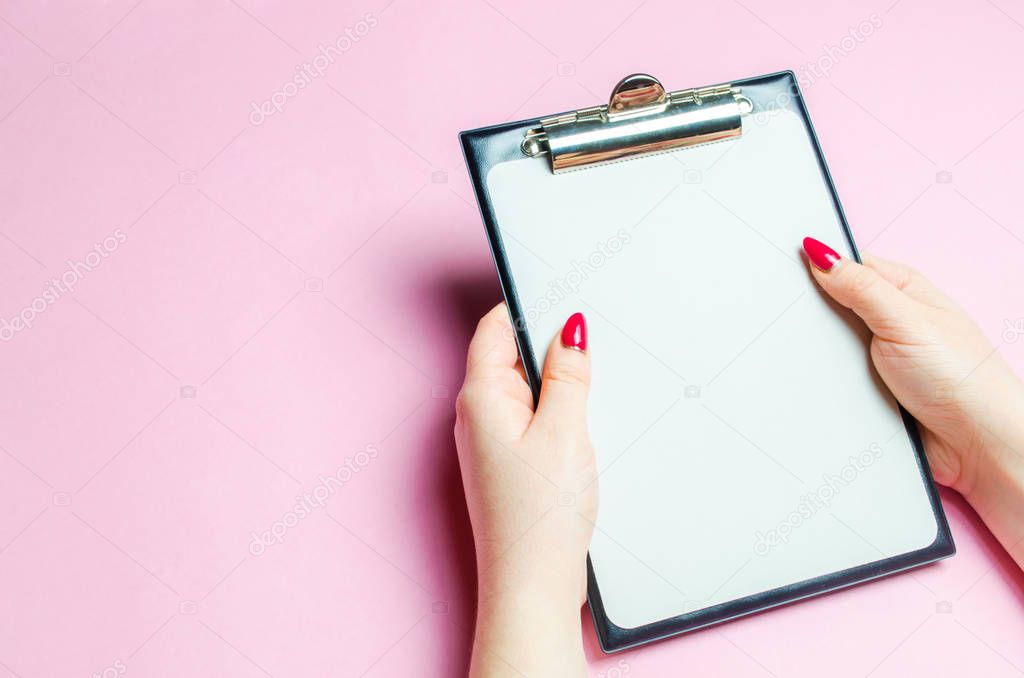 The girl holds an empty tablet for records on a pink background. The concept of control and inventory. Records and work process. Accounting, recording information. Place for text.