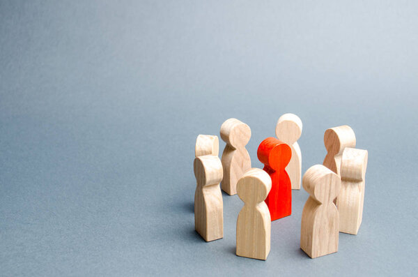 A circle of people surrounds a red person. Communication. Business team, teamwork, team spirit. Wooden figures of people. A circle of people. discussion, cooperation, cooperation. Selective focus
