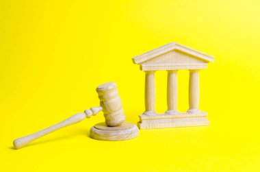 Ahşap yargıç çekiç ve sarı bir arka plan üzerinde hükümet binası. Mahkeme. Devlet yargı sistemi kavramı. Yasaklar ve suç, baskı, özgürlük ve hakların kısıtlanması