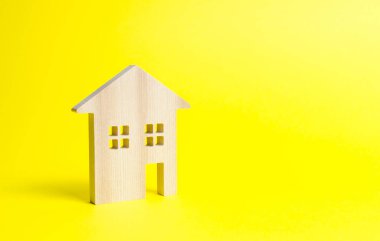 Sarı bir arka plan üzerinde ahşap konut evi. Satın alma için ipotek ve kredi. Minimalizm. İzole Emlak kavramı, uygun fiyatlı konut satın alma, gayrimenkul satış ve kiralama. Emlak vergisi