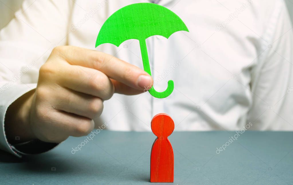 An insurance agent holds a green umbrella over a human figure. Concept of life and health insurance. Unconditional income. Protection of rights. Security. Legal assistance. Golden parachute