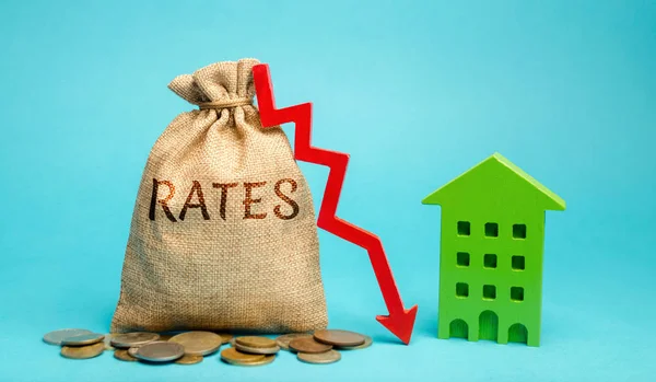 Money bag with the word Rates, down arrow and wooden house. The concept of reducing interest rates on mortgages. Low rental rate for housing. Real estate market and loan. — Stock Photo, Image