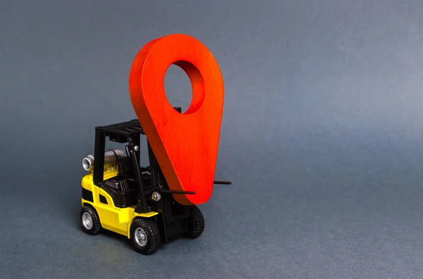Yellow forklift carries a red location pointer. Transportation services and logistics management in production warehouse. Destination cargo and parcels, tracking. Technological processes at factory