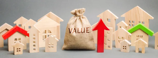 A money bag with the word Value, wooden houses and an up arrow. Concept of real estate market growth. High rental and mortgage rates. The concept of increasing housing prices. Rising rent. — Stock Photo, Image