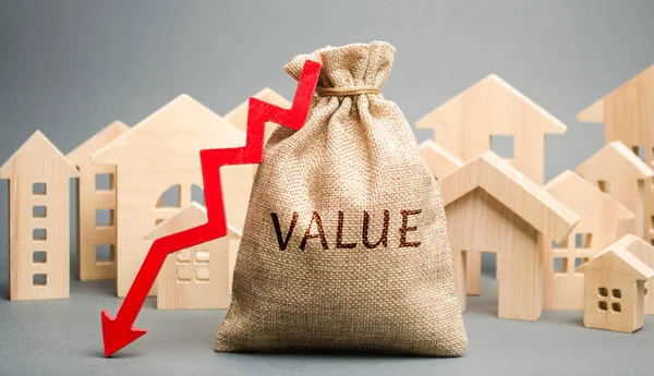 A money bag with the word Value, wooden houses and down arrow. The concept of reducing the market prices of real estate. Low price for renting a house or apartment. Reduced rental and mortgage rates — Stock Photo, Image