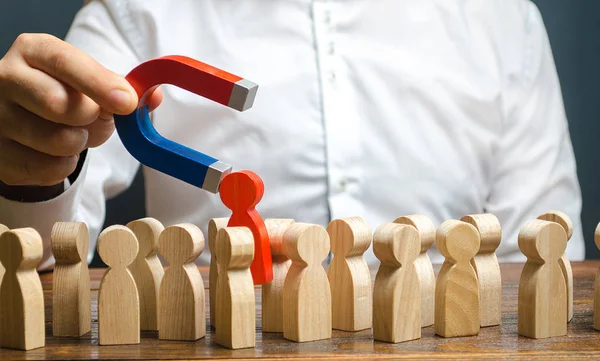 De leider met een magneet trekt een rode menselijke figuur uit de menigte. Identificeer onloyale, repressie, Dissent. toxische, niet-competente werknemer. beheert het bedrijf. Kandidaat voor werk, talent. Human resources — Stockfoto