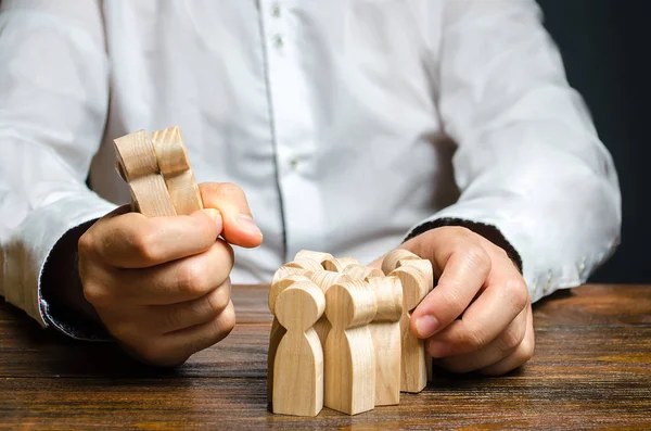 Een man grijpt een beeldje van mensen uit de menigte. Werknemers inhuren. Marktsegmentatie en niche verovering. Human resources. Aansporing van werknemers en klanten van een concurrent. roofzuchtige concurrentie — Stockfoto