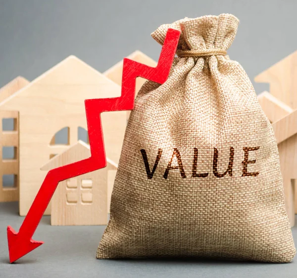 A money bag with the word Value, wooden houses and down arrow. The concept of reducing the market prices of real estate. Low price for renting a house or apartment. Reduced rental and mortgage rates — Stock Photo, Image