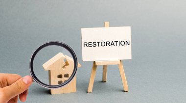 Restorasyon yazıtlı bir poster ve kırık ahşap bir ev. İkincil konutları onarın. İyileştirme süreci, evin yeniden inşası. Yangın veya doğal afet sonrası iyileşme