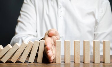 İşadamı domino taşının düşüşünü durdurdu. Risk yönetimi konsepti. Başarılı, güçlü bir iş ve problem çözme. Güvenilir bir lider. Yıkıcı işlemleri durdurun. Strateji geliştirme. Borç yeniden yapılandırması
