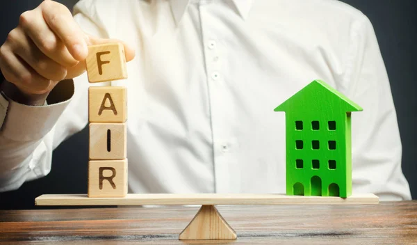 Wooden blocks with the word Fair and a wooden house. Fair value of real estate and housing. Property valuation. Home appraisal. Housing evaluator. Legal transparent deal. Apartment purchase / sale. — Stock Photo, Image