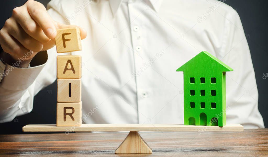 Wooden blocks with the word Fair and a wooden house. Fair value of real estate and housing. Property valuation. Home appraisal. Housing evaluator. Legal transparent deal. Apartment purchase / sale.