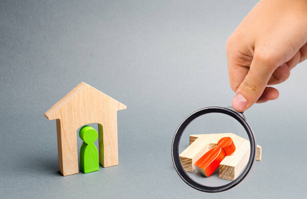 Увеличительное стекло смотрит на целый и разрушенный дом с людьми на темном фоне. плохие соседи, безразличие, стихийные бедствия и катастрофы. Военный конфликт. Перевернутый деревянный дом
