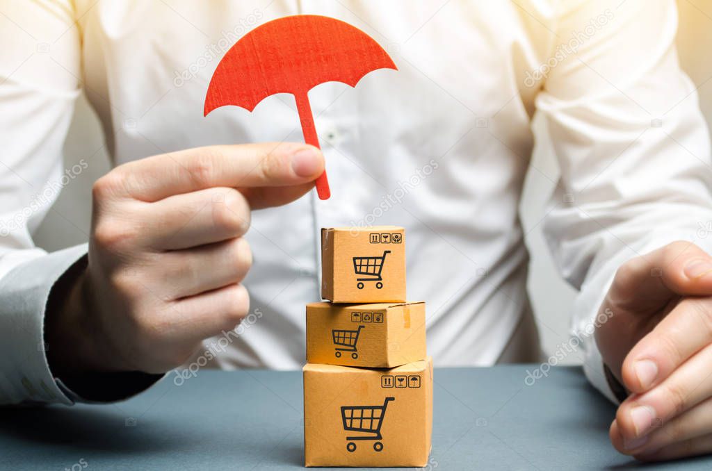 A man holding an umbrella above the boxes. Insurance of purchases and parcels, money back guarantee and non-damage to the goods upon shipment. Internet trade, commerce, market. Free trade zone.