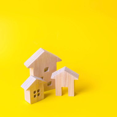 Sarı arka planda üç ev. Gayrimenkul alım satımı, inşaat. Bir şehir veya yerleşim de daire ve konut binaları. Yatırım. mortgage kredisi. Konut Bakımı