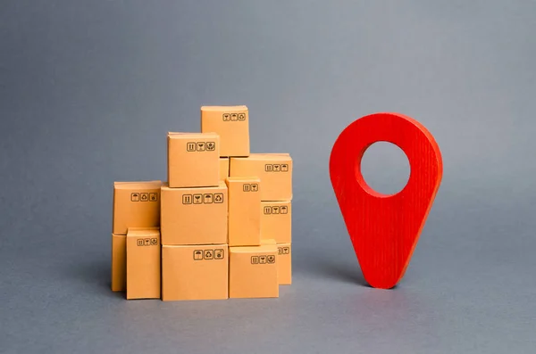 Veel kartonnen dozen en een rode positie pin. Het lokaliseren van pakketten en goederen. Pakketten traceren via internet. Algoritme voor het construeren van een minimum route voor de levering van orders. Wereldhandel — Stockfoto