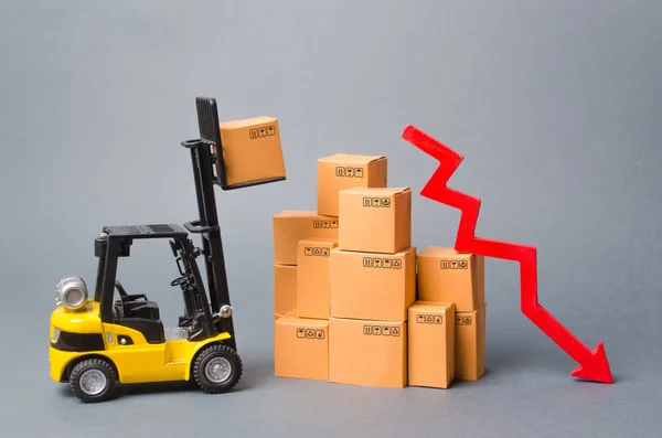 Sárga targonca teherautó truckvet egy doboz alatt egy köteg dobozok és piros nyíl lefelé. A gazdasági arányok csökkenése, az áruk iránti alacsony kereslet, a behozatal vagy a kivitel csökkenése. Csökkentett raktározás, logisztikai költségek — Stock Fotó