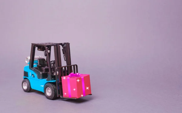 Blauwe vorkheftruck draagt een roze geschenk doos met een strik. Aankoop en levering van een cadeau. Retail, kortingen en wedstrijden. wedstrijd promoties. Verhoog de omzet en trek nieuwe klanten aan. — Stockfoto