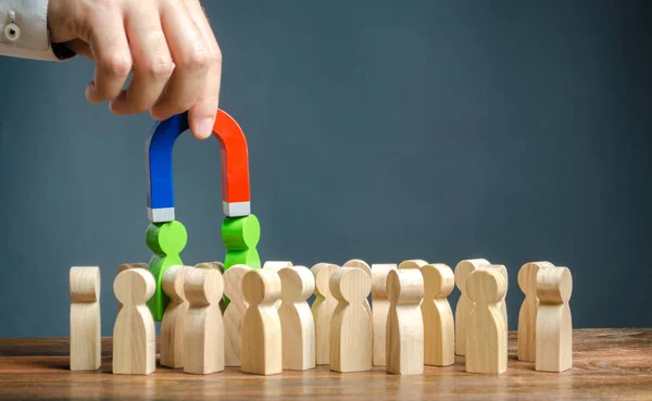 Zakenman met een magneet trekt groene figuren van mensen uit de menigte. Werven van nieuwe werknemers. Zoek getalenteerde werknemers met een groot carrière potentieel. Oprichting van een nieuw business team van sollicitanten. — Stockfoto