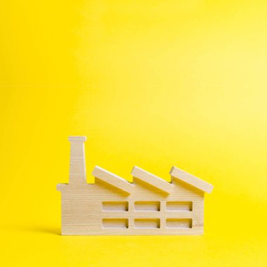 Sarı bir arka plan üzerinde bir bitki veya fabrika ahşap heykelcik. Hammaddegeri dönüşüm. Sanayi ve üretim kavramı. Yeni fabrikaların inşaatına yapılan yatırımlar.