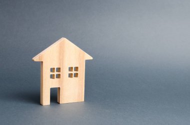 Gri bir arka plan üzerinde ahşap konut evi. Satın alma için ipotek ve kredi. Minimalizm. Gayrimenkul kavramı, uygun fiyatlı konut satın alma, gayrimenkul kiralama. Emlak vergisi.