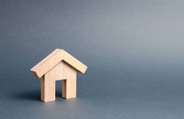 Gri bir arka plan üzerinde küçük ahşap konut evi. Satın alma için ipotek ve kredi. Minimalizm. Gayrimenkul kavramı, uygun fiyatlı konut satın alma, gayrimenkul kiralama. Emlak vergisi.