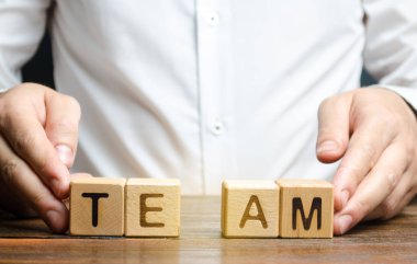 A businessman joins together two parts of the word Team. personnel management, the organization and creation of working groups and teams, the creation of links between individual teams and departments clipart