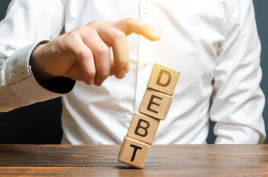 Bir işadamı Borç kelimesi ile küpler bir kule aşağı iter. mali rahatlama kavramı, kredi yeniden yapılandırılması. Finansal istikrar ve bağımsızlık. Devletin iç ve dış borçlarının azaltılması.