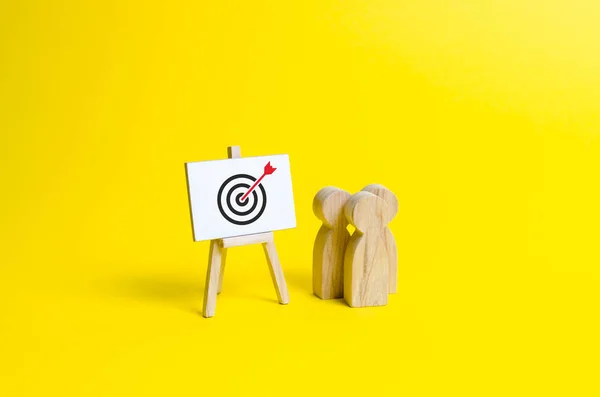 People are standing near the canvas with arrow symbol in the center of the target. Targeting and marketing, advertising. Presentation of information on income and expenses, achievement of goals — Stock Fotó