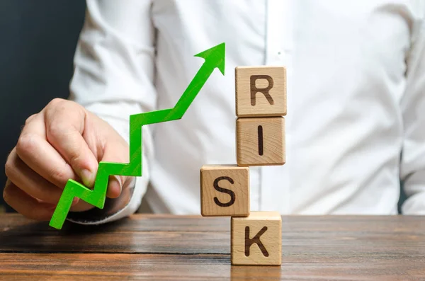 Бізнесмен тримає зелену стрілу вгору біля слова "ризик". Підвищення ділової стійкості, зменшення ризиків і витрат. Розвиток та зміцнення фінансово-економічних систем. Бізнес стратегія . — стокове фото