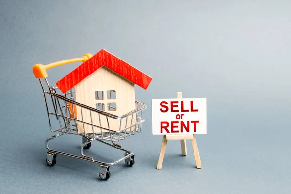 House in a shopping cart and a stand with the inscription sell or rent. rental or selling a home. Real estate liquidity, investment and savings. Real estate market, supply and demand, financial bubble