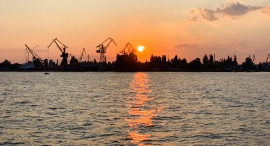 Gün batımında gemileri olan nehir limanı. Trafik arteri meşgul. Lojistik ve altyapı. Gemi yükleme ve boşaltma, ticaret trafiği. Endüstri ve ekonomi. Bitkiler ve fabrikalar. Nakil merkezi. Dnipro.