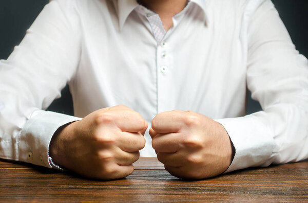 Мужчина держит кулаки на столе. Конец терпения. Это невозможно вынести. Приступ гнева, стресса. Решающий, эмоциональный жест. Импульсивные мужчины. Хватит уже! Холерик
