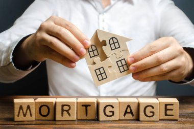 Bir adam yazıt Mortgage üzerinde bulmacalar bir ev toplar. Kendi konut binanızın inşaatı. Kredi kredisi ile ev satın almak, yaşam koşullarının iyileştirilmesi