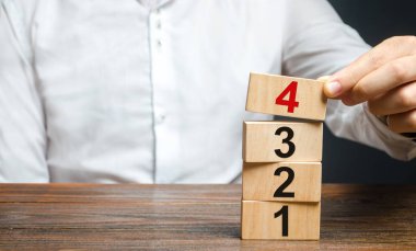 Bir adam üst üste numaralı ahşap bloklar koyar. Alternatif öğeler ve uygulama koşulları. Sözleşmeli yol haritası. Organizasyon ve sistematizasyon, adım adım talimatlar.
