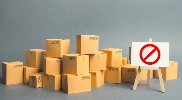 Many cardboard boxes and a sign stand with red symbol NO. Embargo, trade wars. Inability to sell products, ban on the import. Restriction on the importation of goods, proprietary for business. — Stock Photo, Image