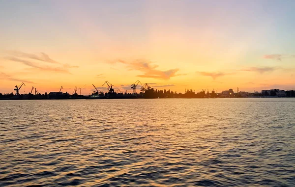 Flusshafen mit Schiffen bei Sonnenuntergang. Befahrene Verkehrsader. Logistik und Infrastruktur. Be- und Entladen von Schiffen, Handelsverkehr. Industrie und Wirtschaft. Pflanzen und Fabriken. Verkehrsknotenpunkt. Dnipro — Stockfoto